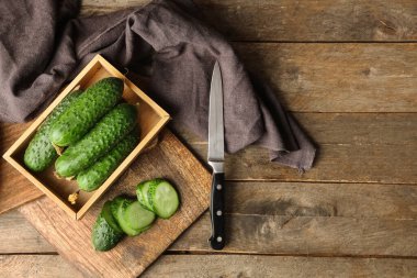 Tahta arka planda taze yeşil salatalıklı kutu ve yemek.