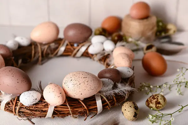 Güzel geleneksel Paskalya çelengi hafif arka planda tüy ve yumurtalarla süslenmiş.