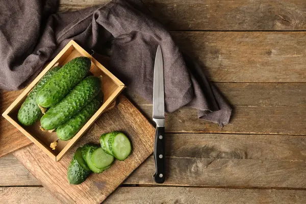 Tahta arka planda taze yeşil salatalıklı kutu ve yemek.