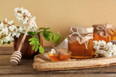 Bir kâse bal ve akasya çiçekli ahşap masa.