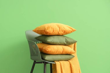 Yeşil duvarın yanında yastık yığını olan sandalye