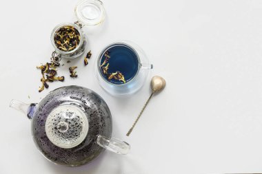 Çaydanlık, mavi organik çay ve beyaz arka planda kavanozda bezelye çiçeği çayı.