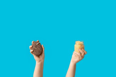 Mavi arka planda deniz tuzu ve sünger taşı şişesini tutan kadın eller.