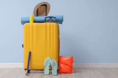 Mavi duvarın yanında toplanmış bavullar ve plaj aksesuarları.