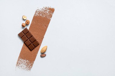 Lezzetli çikolatalı kompozisyon, kakao tozu ve hafif arka planda fındık.