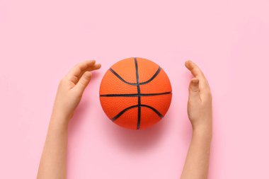 Pembe arka planda basketbol oynamak için çocuğun elleri, yakın plan