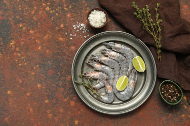 Koyu arkaplanda taze çiğ karides ve limon tabağı.