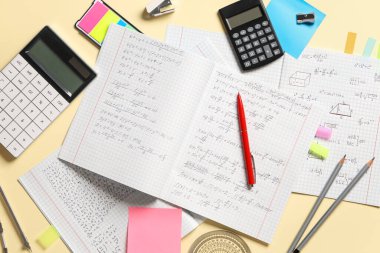 El yazısıyla yazılmış matematik formülleri ve sarı arkaplanda kırtasiye kitapları