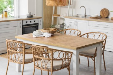 Açık mutfakta hasır sandalyeli yemek masası.