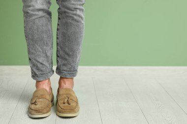 Yeşil duvarın yanında şık ayakkabılı genç adam, yakın plan.