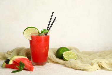 Bir bardak taze karpuz suyu, beyaz arka planda limon ve nane.