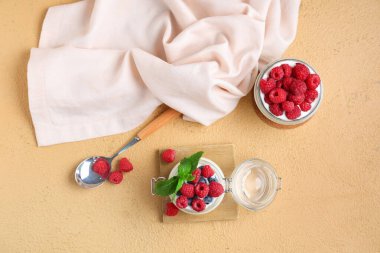 Kahverengi arka planda taze ahududu ve yabanmersini dolu kavanozlar dolusu lezzetli yoğurt.