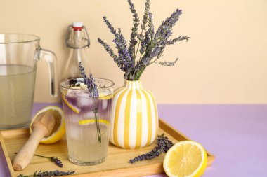 Çiçekli taze lavantalı limonata ve renkli arka planda ahşap sıkacağı.