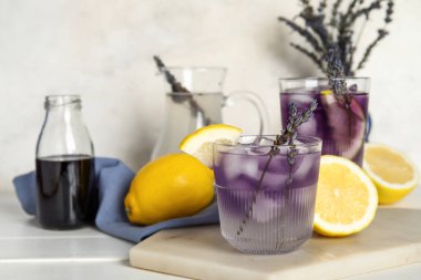 Soğuk lavantalı limonata, şurup ve açık ahşap masada limon.