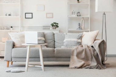 Oturma odasında dizüstü bilgisayarı olan rahat bir kanepe ve kahve masası.