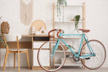 Çalışma odası, raf ünitesi ve bisiklet beyaz tuğla duvarın yanında.