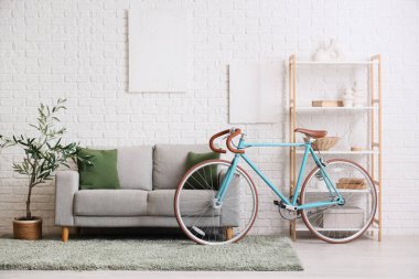 Koltuk, raf ünitesi, dekoratif ağaç ve bisiklet oturma odasının içinde.