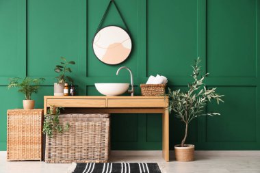 Lavabolu, aynalı, sepetli ve banyonun içindeki çiçekli masa.