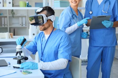 Klinikteki masada mikroskop kullanan erkek doktor.