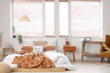 Yatak odasının içi büyük yatak ve komodinlerle dolu.