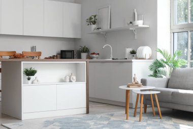 Modern bir stüdyo daire mutfak tezgahı, şık bir kanepe ve pencere kenarındaki masa.