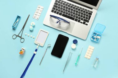 Mavi arka planda dizüstü bilgisayarı ve tıbbi malzemeleri olan cep telefonu. Teletıp kavramı