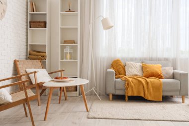 Lambası, koltuğu ve kanepesi olan bir oturma odası.