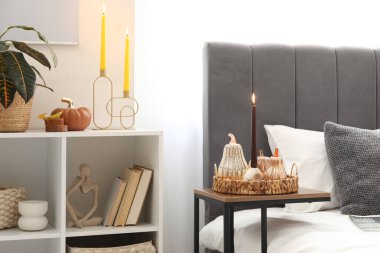 Yatak odasındaki masada yanan mum olan dekoratif balkabakları.