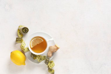 Bir fincan diyet çay, limon, zencefil kökü ve arka planda şerit. Kilo verme konsepti