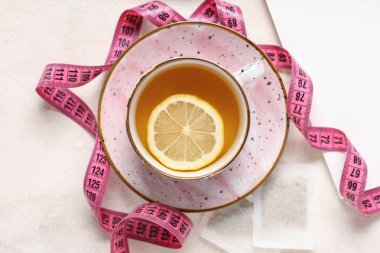 Kilo vermek ve beyaz grunge masasında şerit çekmek için bir fincan çay.