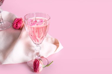 Bir bardak lezzetli pembe şarap, taç yaprakları ve güzel güller.