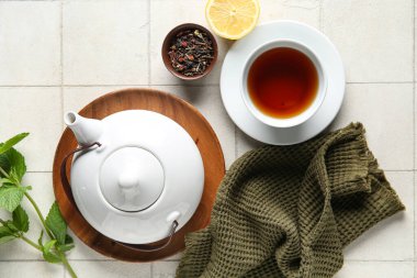 Çay demliği, çay fincanı, limon ve peçeteyle harika bir kompozisyon.