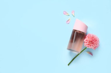 Bir şişe parfüm, yıldız çiçeği ve mavi arka planda taç yaprakları.