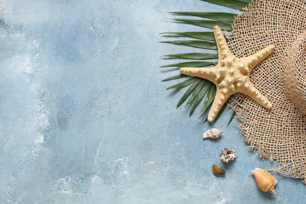 Şapkalı, deniz kabuklu ve mavi grunge arkaplanlı güzel bir kompozisyon.