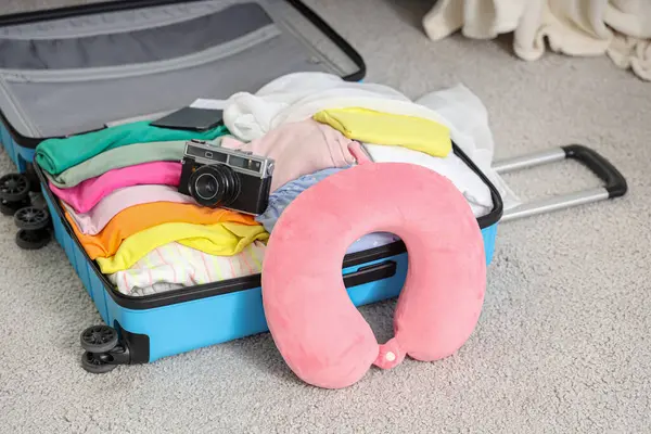 Odada yerde boyun yastığı olan bavulu aç. Seyahat kavramı