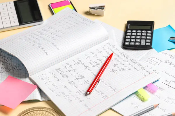 El yazısıyla yazılmış matematik formülleri ve sarı arkaplanda kırtasiye kitapları