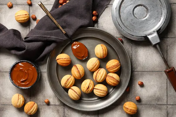 Lezzetli ceviz şekilli kurabiye tabağı, kaynamış süt ve gri kiremitli masada pişirme formu.