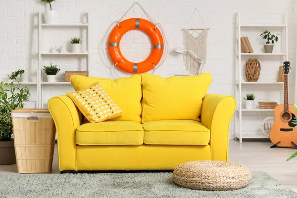 Konforlu kanepe, raflar ve oturma odasındaki beyaz tuğla duvarda can simidi halkası.