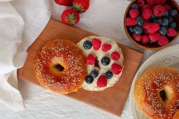 Beyaz arka planda tereyağlı ve böğürtlenli ahşap simit tahtası