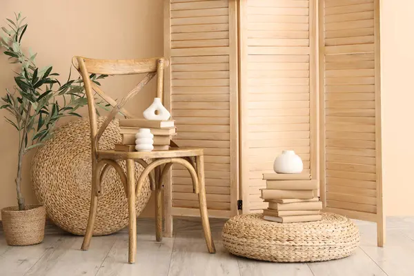 Katlanmış perdeli rahat bir sandalye, bej duvarın yanında sedir ve kitaplar.