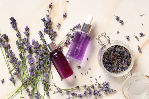 Kurumuş çiçekli lavanta yağı ve kavanozlar mermer arka planda, yakın plan.