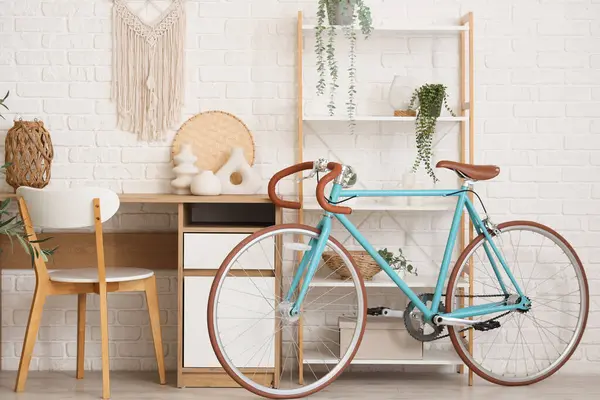 Çalışma odası, raf ünitesi ve bisiklet beyaz tuğla duvarın yanında.
