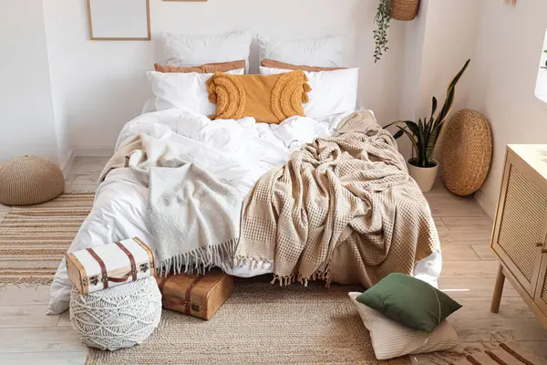 Yatak odasının içinde bavulla büyük, rahat bir yatak ve puf.