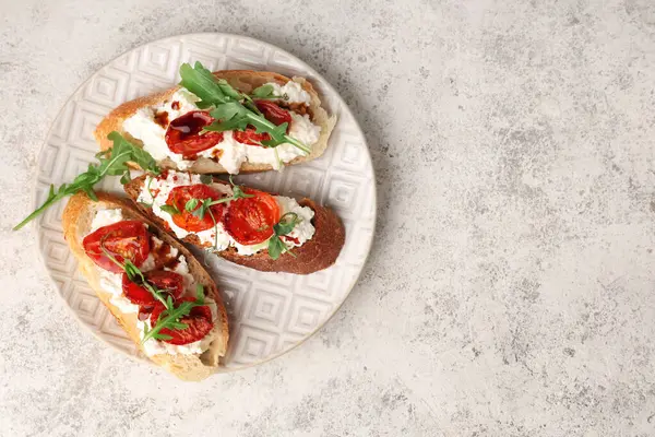 Beyaz arka planda ricotta ve roka ile lezzetli domates bruschetta tabağı.