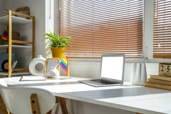 Ofisteki masada LGBT bayrağı ve dizüstü bilgisayarlı vazo