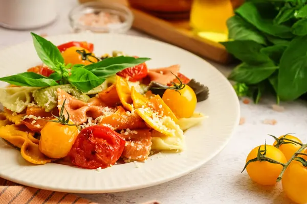 Beyaz arka planda domates ve fesleğenli lezzetli farfalle makarna tabağı, yakın plan.