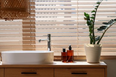 Modern lavabo, ev bitkileri ve banyo malzemeleri banyo penceresinin yanındaki çekmecelerde.