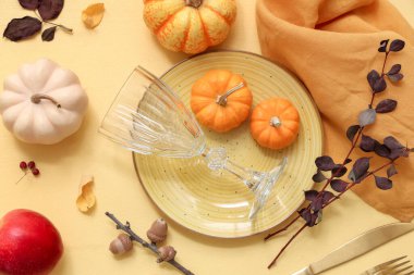 Taze balkabakları, elmaları, meşe palamutları, dalları ve sarı arka planda sonbahar yaprakları olan güzel masa ortamları.