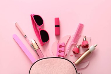 Pembe arka planda çanta, kozmetik ve aksesuarlarla kompozisyon