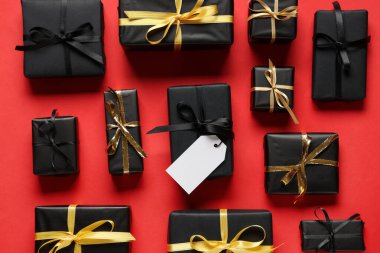 Kırmızı arka planda boş karton etiketli hediye kutuları. Kara Cuma indirimi